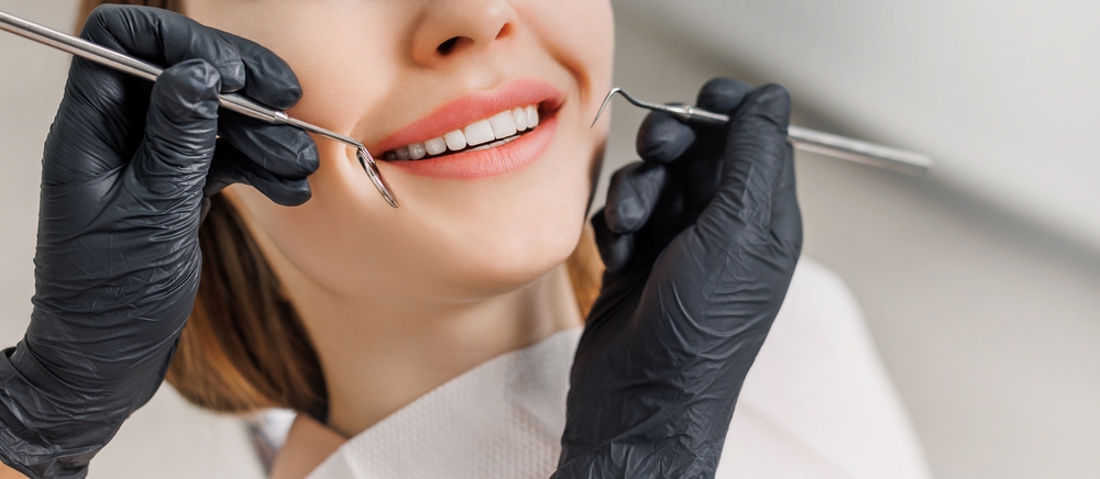 Banner for dental theme. Close-up of female smile with white teeth during medical examination. Concept of tooth whitening, treatment, veneers, professional clinic. Photo with free copy space.