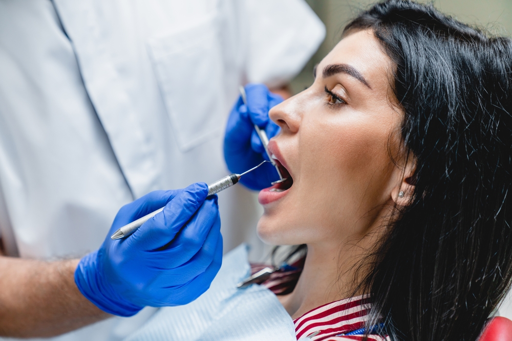 Beautiful caucasian woman visiting dentist orthodontist, whitening her teeth, filling tooth. Orthodont curing caries, examining mouth cavity decay.