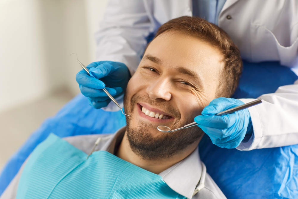 Dental health. Man sits comfortably in dentists chair, showing off white smile that exudes confidence.
