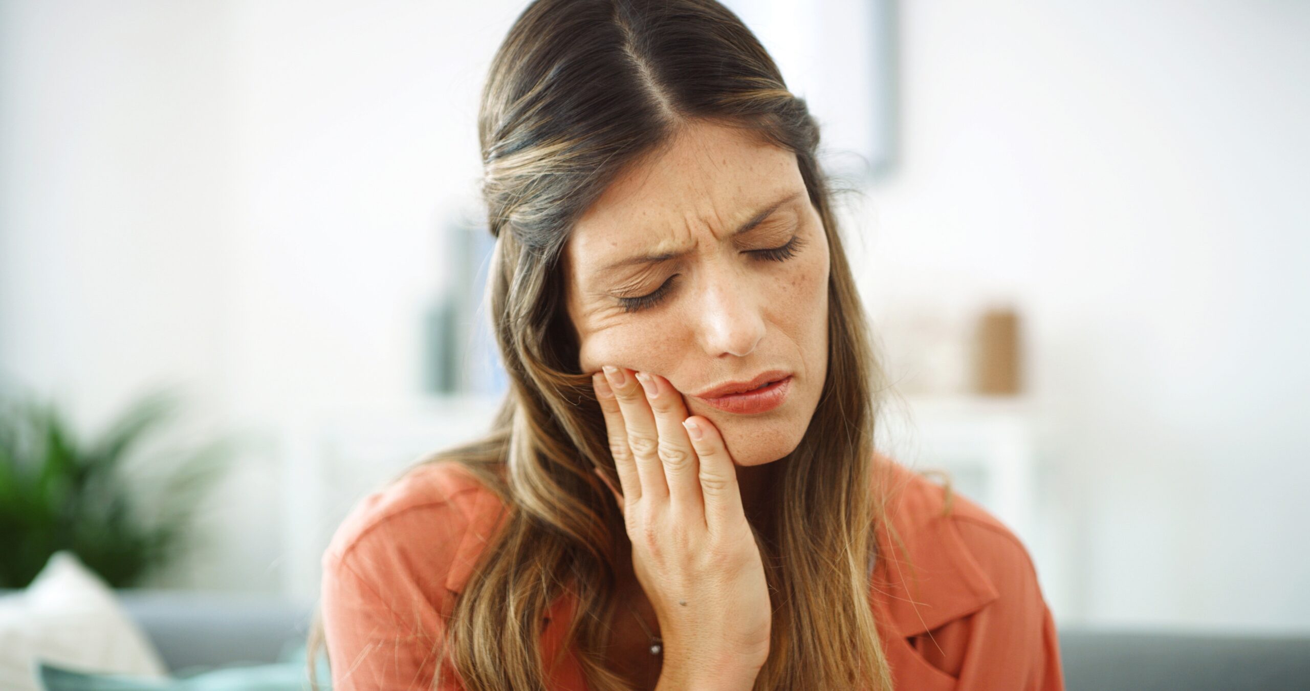 Woman holding cheek with discomfort, showing symptoms that may require gum disease treatment – Gum Disease Treatment Highland Park